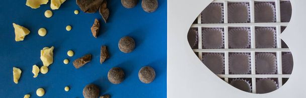Stücke natürlicher dunkler und weißer Schokolade sowie eine herzförmige Geschenkschachtel für Süßigkeiten liegen auf blauem Hintergrund - Foto, Bild