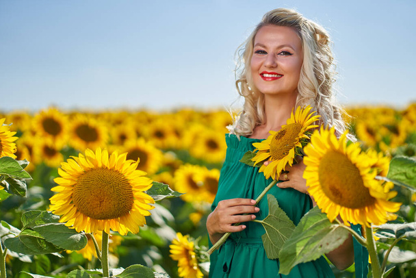 Beautiful blonde Caucasian woman in a sunflower field - Foto, Imagen