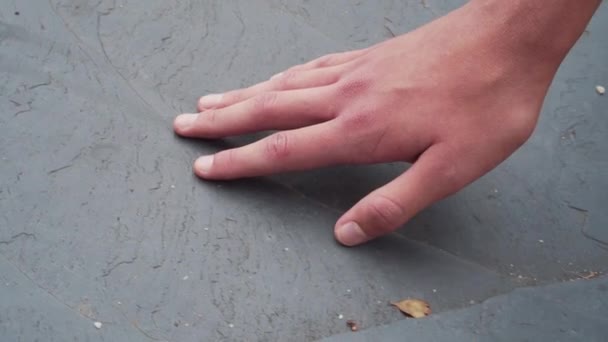 Boy touches the stone textured gray surface with his hand, feeling the rough natural mountain rock. Tactile touch. Swipes hand from left to right. close-up view - Video