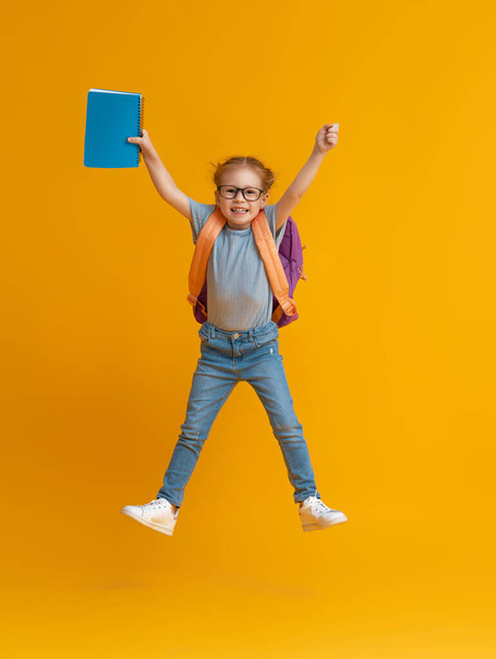 Back to school and happy time! Cute industrious child on color paper wall background. Kid with backpack. Girl ready to study. - Photo, image
