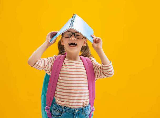 Back to school and happy time! Cute industrious child on color paper wall background. Kid with backpack. Girl ready to study. - Foto, Bild