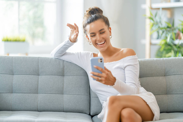 Young woman is using phone for video call. Funny girl having fun staying at home. - Fotoğraf, Görsel