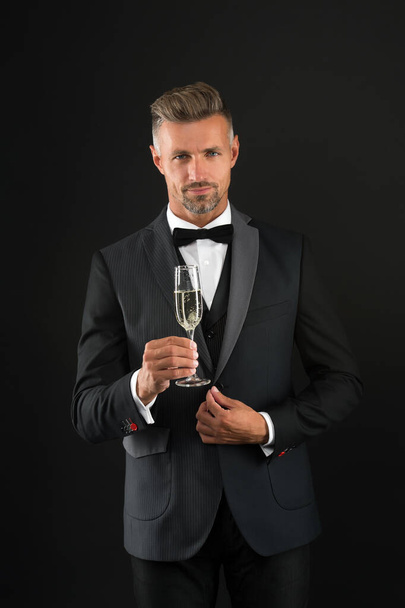 Przystojny mężczyzna smokingi garnitur pić szampan czarny tło, świętować rocznicę koncepcji - Zdjęcie, obraz