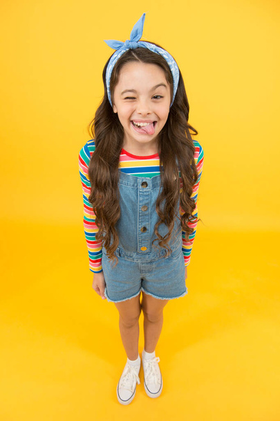 Fun lifestyle little girl long hair denim overalls, cheerful grimace concept - Photo, Image