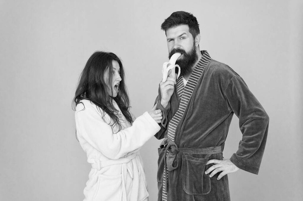 Food for health. Healthy breakfast. Couple sleepy faces domestic clothes eat banana. Couple in love bathrobes. Advice relationships surviving quarantine. Morning routine. Sharing food. Healthy food - Фото, изображение