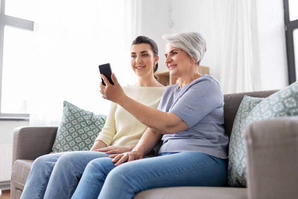 senior mother with daughter taking selfie at home - Photo, Image
