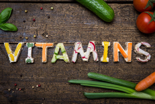 letters of fresh vegetable canapes builds the word vitamins on a old wooden table - Photo, image