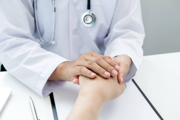 The female doctor uses a friendly hand to hold the patient's hand to give confidence and show care about health care. Medical concepts and good health. - Photo, Image