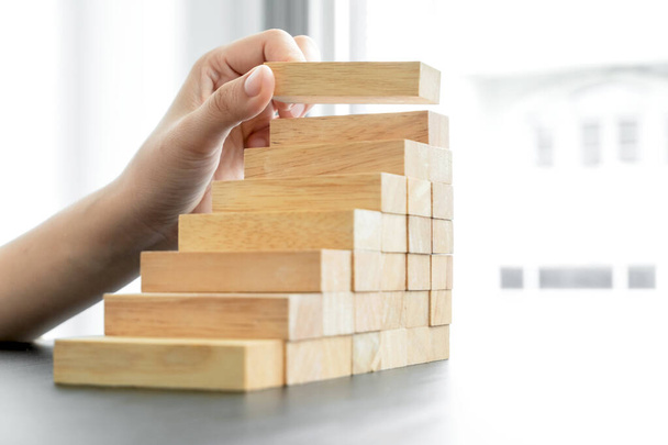 Manos de empresarias jugando a bloques de madera. Concepto Riesgo de gestión y planes de estrategia para el crecimiento y el éxito empresarial. - Foto, imagen
