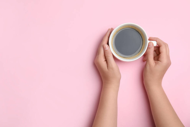 Woman with cup of coffee on light pink background, top view. Space for text - Foto, Imagem