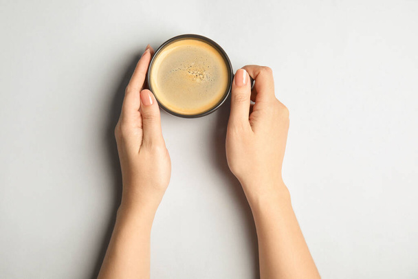 Woman with cup of coffee on light background, top view - Foto, Imagen