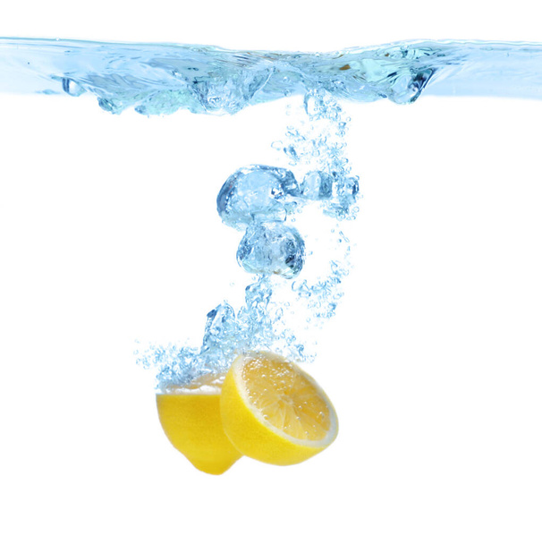 Cut lemon falling down into clear water against white background - Foto, Bild