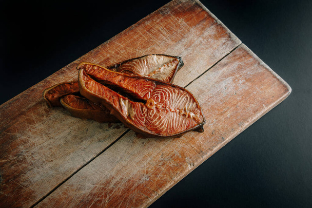 Slice of smoked salmon on vintage  cutting board - Fotó, kép