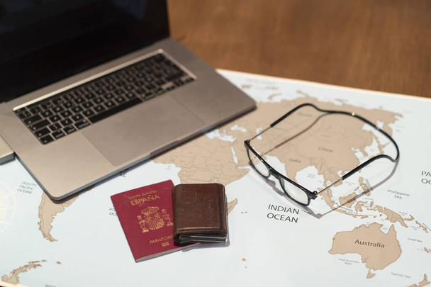 τραπέζι με παγκόσμιο χάρτη και φορητό υπολογιστή και διαβατήριο - Φωτογραφία, εικόνα