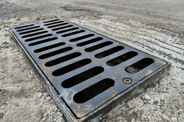 New rainwater grate on the road or sidewalk, installation in concrete. City sewage system for draining water during heavy rain - Photo, Image