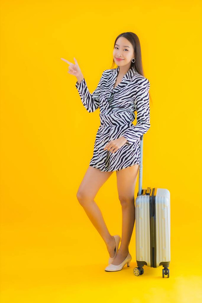 Muotokuva kaunis nuori aasialainen nainen matkustaa matkatavaroiden passi ja lennolle pass keltainen eristetty tausta - Valokuva, kuva