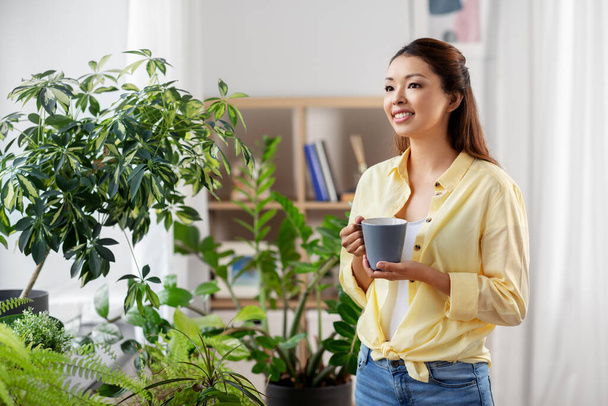 happy smiling asian woman drinking coffee at home - Фото, зображення