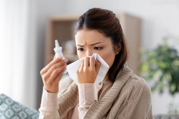 sick asian woman with nasal spray medicine at home - Фото, изображение