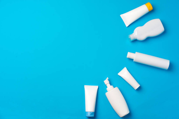 Bottles of sunscreen cream on blue background - Фото, изображение