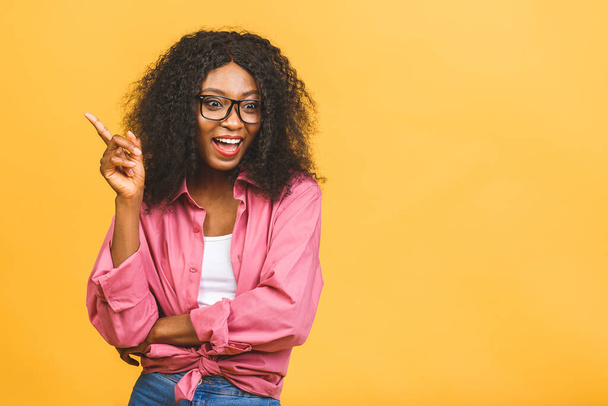 Portret szczęśliwej afrykańskiej czarnej kobiety wskazuje palcem wskazującym puste miejsce na kopię, pokazuje miejsce na reklamę lub tekst promocyjny. Palec wskazujący - Zdjęcie, obraz