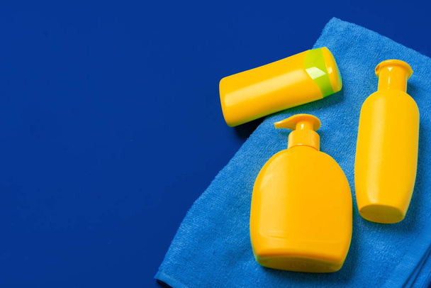 Bright yellow bottles of sunscreen product on dark blue paper background - Photo, image