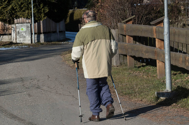 Stary człowiek z chodzącymi kijami chodzi po ulicach - Zdjęcie, obraz