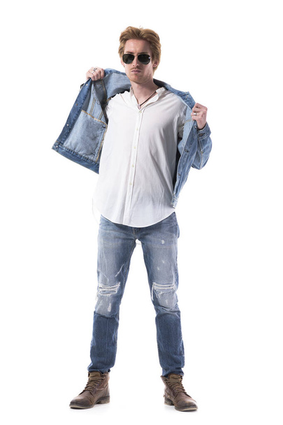 Selbstbewusster junger gutaussehender Mann in Jeans, der sich eine Jeansjacke anzieht. Volle Körperlänge isoliert auf weißem Hintergrund.  - Foto, Bild