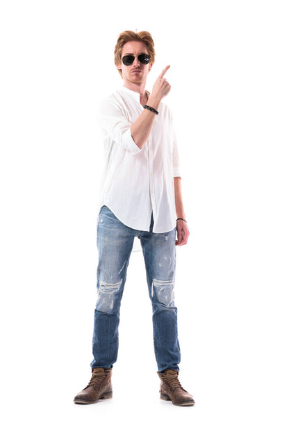 Confident successful young stylish man advertising and pointing finger upwards at side. Full body length isolated on white background.  - Fotó, kép