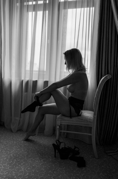 naked girl with a beautiful body wears stockings on the background of the window - Foto, Bild