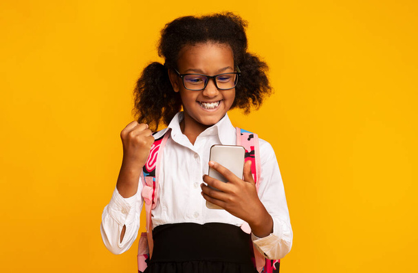 Joyful Black Schoolgirl With Smartphone Gesturing Yes, Studio Shot - Foto, Imagen