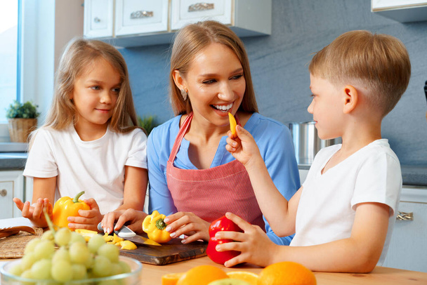 Mother cooking with her children in kitchen - Photo, image