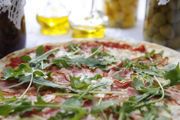 Pizza with ripening ham and arugula.Traditional Italian pizza. Suggestion to serve a dish. Food background. - Foto, imagen