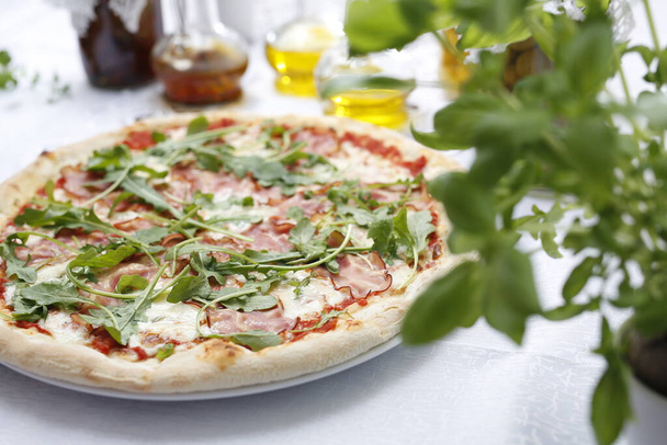 Pizza with ripening ham and arugula.Traditional Italian pizza. Suggestion to serve a dish. Food background. - Foto, afbeelding