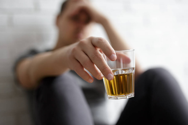 молодой человек, страдающий алкоголизмом, закрывает стакан виски в мужской руке - Фото, изображение
