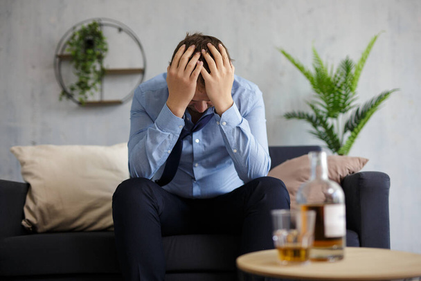 Alkoholismus, Depression, Krise und Konkurskonzept - depressiver Geschäftsmann trinkt Alkohol zu Hause oder im Büro - Foto, Bild