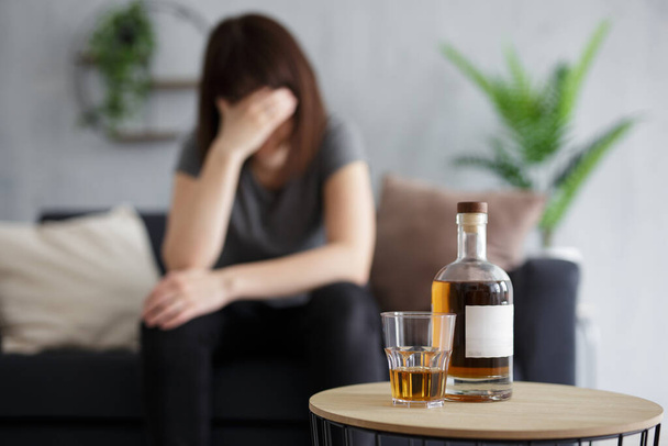 vrouwelijk alcoholisme en depressie concept - jonge vrouw huilen en alcohol drinken thuis - Foto, afbeelding