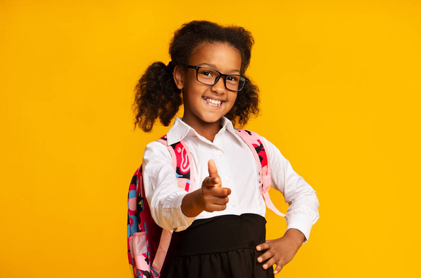 Щаслива афроамериканська школярка вказує пальцем на камеру в студії
 - Фото, зображення