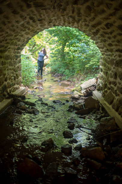 Abstract woman through tunnel by forest stream in defocused background - Photo, Image