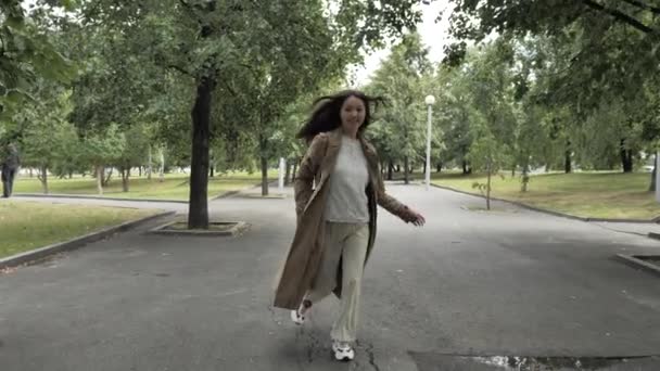 Young beautiful girl with long hair runs down an alley along the trees - Metraje, vídeo