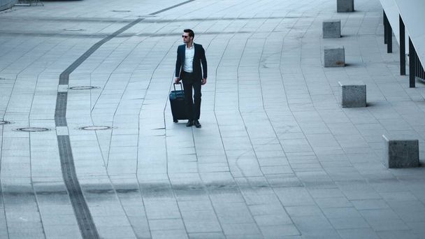 Closeup businessman walking with luggage. Man checking time on wristwatch - Foto, immagini