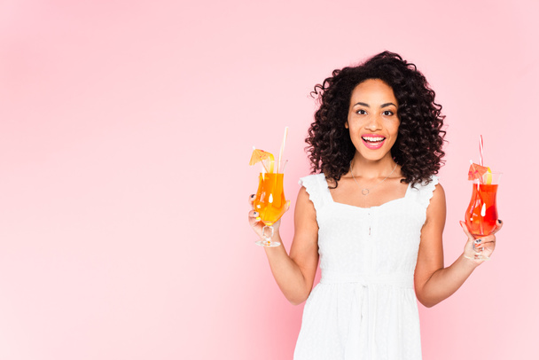 joyeuse fille afro-américaine tenant des cocktails sur rose  - Photo, image