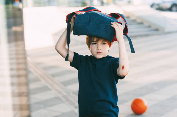Ein müder Junge in Sportuniform und mit einer Wunde am Arm kehrt nach dem Basketballtraining nach Hause zurück. Bildung, Erziehung - Foto, Bild