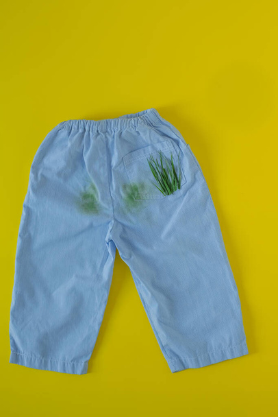 kojenecké kalhoty v skvrnách trávy.izolované na žlutém pozadí - Fotografie, Obrázek