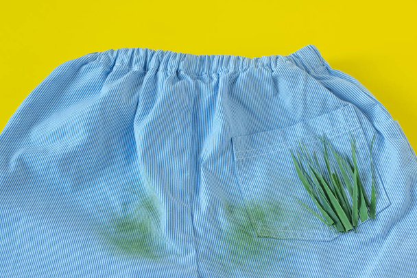 pantalones de bebé en manchas de hierba. Aislado sobre fondo amarillo - Foto, imagen