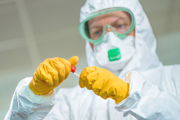 Epidemiologist examining medical sample test tube in virus quarantine, testing the patient's blood during viral infection outbreak - Foto, afbeelding