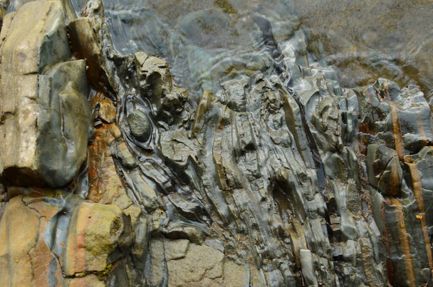 Las capas de roca - las formaciones coloridas de las rocas echadas a lo largo de los centenares de años. Fondo interesante con textura fascinante
. - Foto, imagen