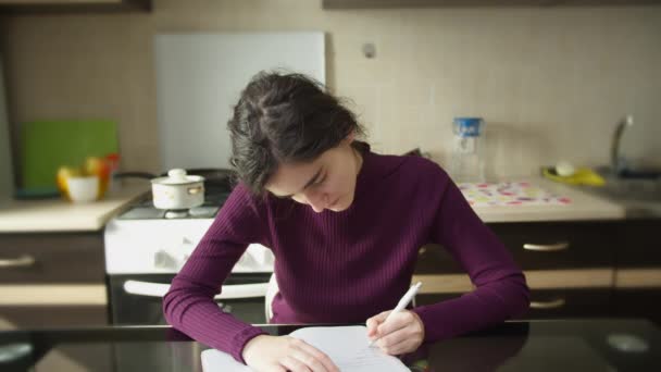 Girl student writes in a notebook, left-handed, learning at home - Video, Çekim