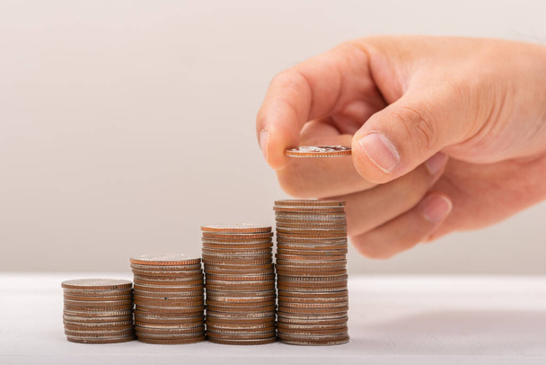 Hand putting coins on stack on table,Saving money concept or Business Growth concept - Photo, Image