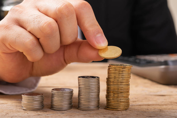 Hand putting coins on stack on table,Saving money concept or Business Growth concept - Photo, image