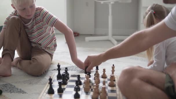A teenage boy plays chess with his father at home - Video